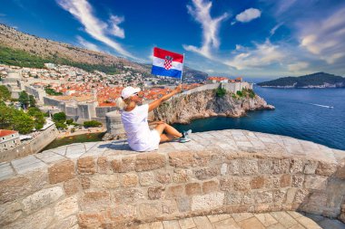 Dubrovnik şehir duvarlarında Hırvat bayrağı taşıyan kız
