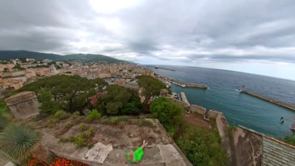 法国科西嘉岛巴斯蒂亚市港口的一个露台上坐着一位女游客的空中照片 泰瑞尼亚海城市港口灯塔的城市景观空中景观 — 图库视频影像
