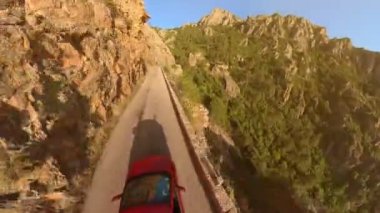 Gün batımında Piana Çorak Toprakları 'nın D81 yolu üzerindeki kırmızı bir arabanın hava görüntüsü. Piana 'lı Les Calanques, Porto Ota kasabasının Akdeniz kıyısındaki Korsika' nın doğal parkı. 360 görünüm