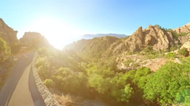 Aerial view of tourist girl walking on D81 route of Calanques of Piana badlands at sunset. Drone view Corsican badlands called Les Calanques in Mediterranean sea by the Porto Ota and UNESCO heritage.