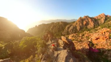 Aerial view of a tourist woman on top aerial view of sunset badlands Calanques of Piana. Drone view on the road in Corsican badlands called Les Calanques in Mediterranean sea by the Porto Ota