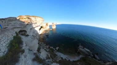 Aerial sunset panorama of the cliffs under Bonifacio walled city in Corsica island of France. Drone view from mount Leone of Bonifacio bay with Secret Beach and King Aragon Steps in Mediterranean sea.