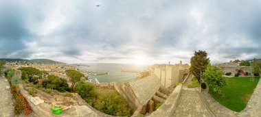 Aerial view of a tourist woman sitting in a terrace on harbor of Bastia city, in Corsica island of France. Aerial view of cityscape with the lighthouse of the city port in Tyrrhenian sea. 360 degrees