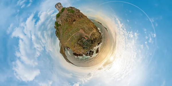 Tiny Planet 360 view in Punta Parata by the Sanguinaires islands. Woman looking sunset by the Parata tower in Corsica island of France. Ancient Genoese tower in Corsica.