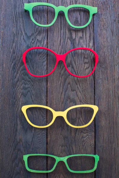 Eyeglass frames of different colours, red, yellow, green on a wooden background. Concept fashion and design, life style. High quality photo
