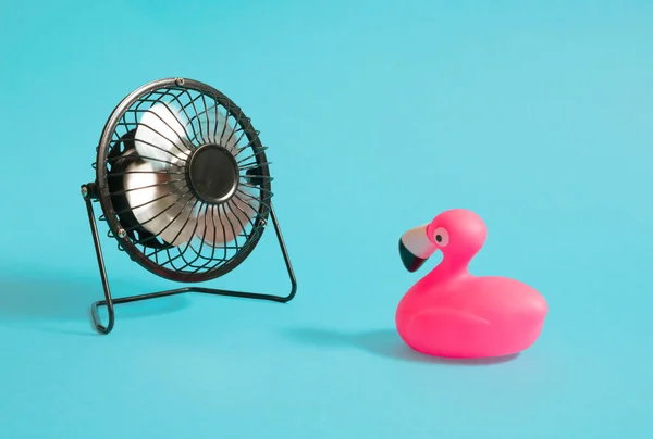 Desk fan and flamingo on a pastel cyan backgrond. Minimal horizontal composition, summer joy concept