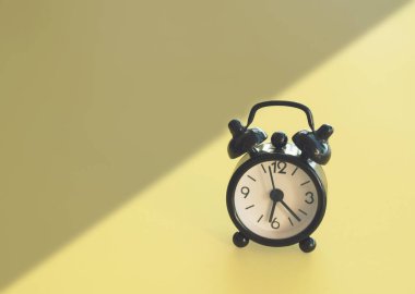 Retro alarm clok between night and day on a yellow background. Horizontal minimal composition, early morning concept