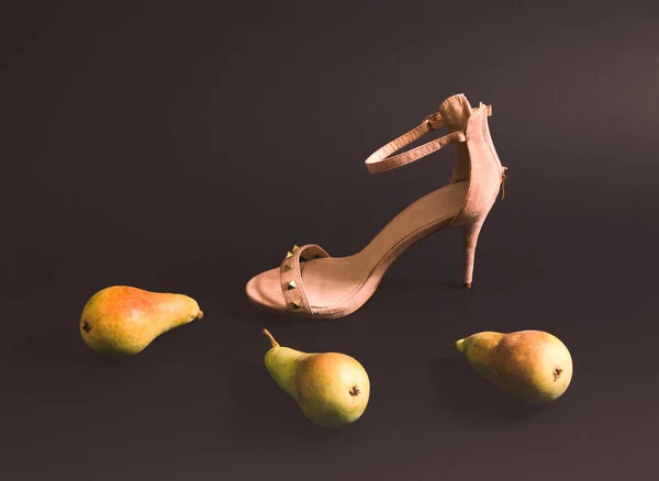 Pears and high heels on a black background. Minimal horizontal composition, modern woman lifestyle concept