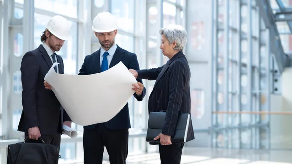 Arquitectos Negocios Multiétnicos Con Cascos Seguridad Discutiendo Plano Pie Vestíbulo — Foto de Stock