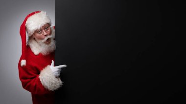 Noel Baba siyah ilan panosunu işaret ediyor. Yazı için fotokopi alanı, şaşırmış yüz ifadesi.