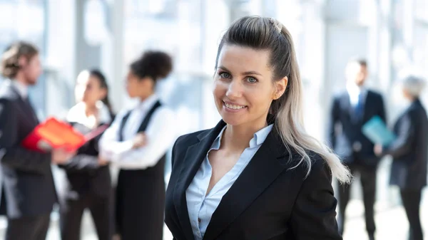 ビジネスビルの同僚の前で正式なスーツ姿の美しい若いビジネス女性 — ストック写真