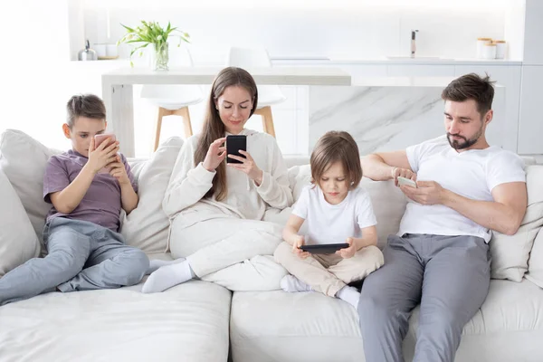 Family Parents Children Sitting Together Sofa Smartphones Home — стоковое фото