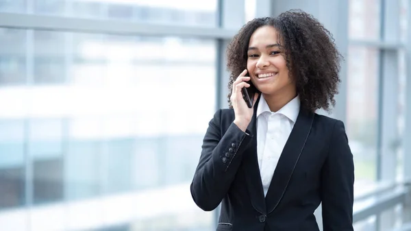 Smiling employee mixed race busines woman talking on a phone in office