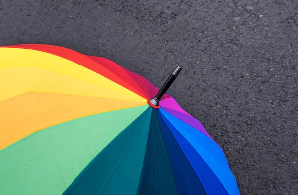 Um guarda-chuva brilhante no asfalto molhado. — Fotografia de Stock