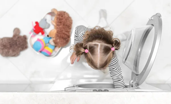 The child puts toys in the washing machine. — Stock Photo, Image