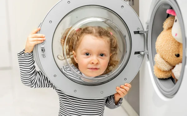 The child looks through the door of the washing machine. — Stock Photo, Image