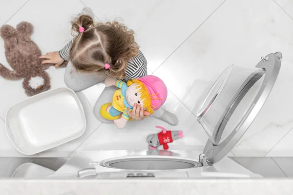 The child puts toys in the washing machine. — Stock Photo, Image
