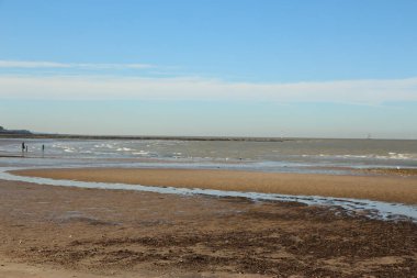 Yazın sonlarına doğru Whitstable, Kent, İngiltere sahillerinde gezinirken su tarafından yapılan kumların manzarasını ve şablonlarını ve çarpan dalgaları görürüz.