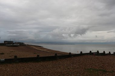 Yazın sonlarına doğru Whitstable, Kent, İngiltere sahillerinde gezinirken su tarafından yapılan kumların manzarasını ve şablonlarını ve çarpan dalgaları görürüz.
