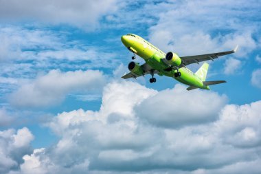 Bulutlu mavi gökyüzünün arka planında havalanan büyük sarı bir S7 uçağı: Abakan, Rusya - 08 Ağustos 2020