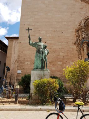 Misyoner Junipero Serra anıtı, İspanya 'nın Balearic Adaları' ndaki Palma, Mallorca 'daki St. Franzesc Bazilikası önünde Hintli bir çocukla birlikte.