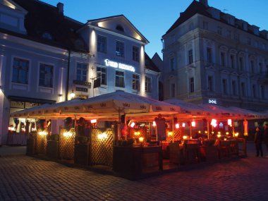 Estonya 'nın Tallinn kentindeki geniş ve popüler kasaba meydanı, akşamları sıcak ışıklarla aydınlatılan samimi restoran ve kafelerle doludur.