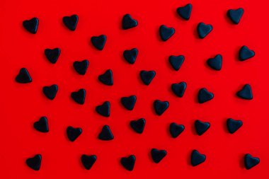Kırmızı arka planda bir sürü siyah kalp var. Kara Cuma ya da Sevgililer Günü konsepti.