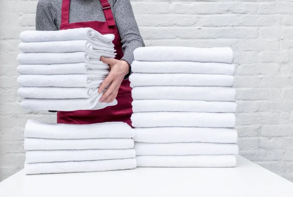 労働者の手は白い背景に洗濯やホテルで多くの白いタオルを保持します ストックフォト