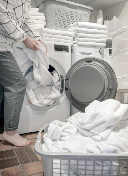 女性の手は洗濯機や乾燥機の近くにタオルを保持 ストックフォト