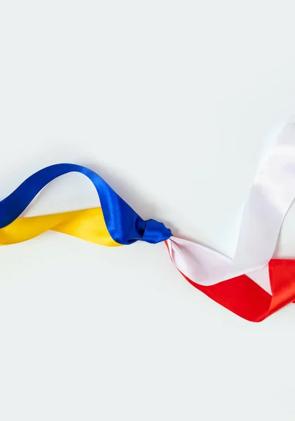ポーランドとウクライナの2つの旗が白地に結び付けられた 戦争中のポーランドからウクライナへの友好と寄付 ストック写真