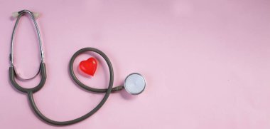 Pembe arka planda steteskop ve kırmızı kalpler. Sağlık hizmeti kavramı..