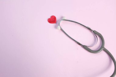 Pembe arka planda kırmızı kalpli bir steteskop tıbbi ekipmanı kopyala. Sağlık hizmeti kavramı..
