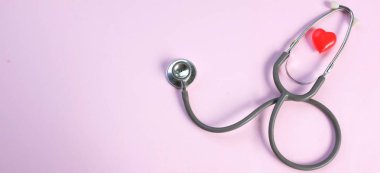Üst manzara, steteskop ve pembe arka planda kırmızı kalpler. Sağlık hizmeti kavramı.