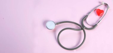 Üst manzara, steteskop ve pembe arka planda kırmızı kalpler. Sağlık hizmeti kavramı.