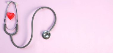 Üst manzara, steteskop ve pembe arka planda kırmızı kalpler. Sağlık hizmeti kavramı.