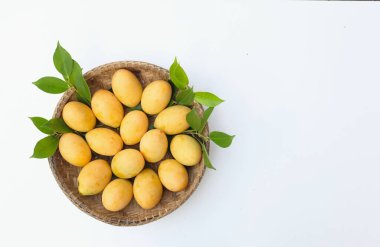 Üst ve düz, olgun sarı bir Marian eriği ya da Tayland bitkisi bambu sepeti içinde beyaz bir arka planda izole bir şekilde yatıyordu.