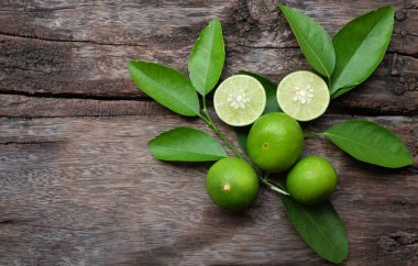 top view and flat lay a fresh raw key limes green and leaves on a wooden table