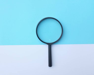 Siyah, renkli kağıt üzerinde büyüteç. Beyaz ve mavi geometrik şekiller. Arama sembolü ve genişleyen berraklık.