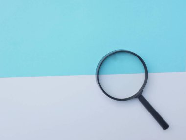 Siyah, renkli kağıt üzerinde büyüteç. Beyaz ve mavi geometrik şekiller. Arama sembolü ve genişleyen berraklık.