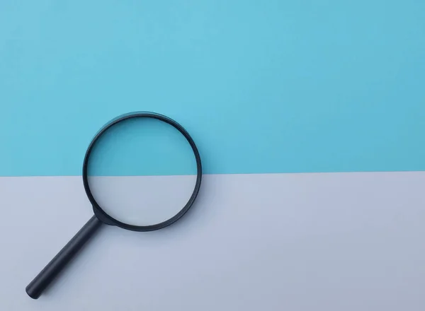Black Magnifying Glass Colored Paper White Blue Geometric Shapes Backgrund — Foto Stock