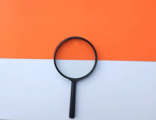 Black Magnifying Glass Colored Paper White Orange Geometric Shapes Backgrund — Fotografia de Stock