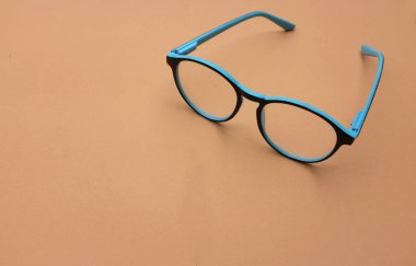 Temiz gözlükler, kahverengi arka planda tel şeritli mavi çerçeveler.
