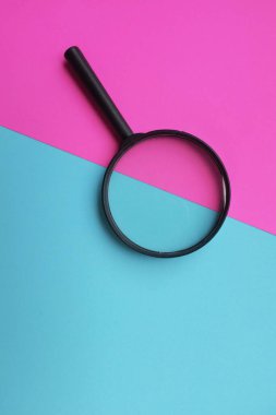 Pembe ve mavi arka planda siyah yuvarlak büyüteç. Kitapları aramak ya da genişletmek için kullanılır.