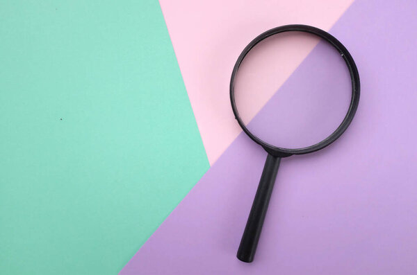 magnifying glass search symbol  on a multi colored paper background