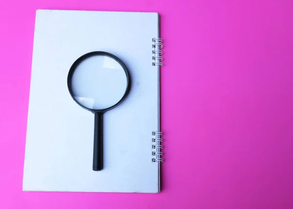 magnifying glass search symbol on  notepads isolate a pink background