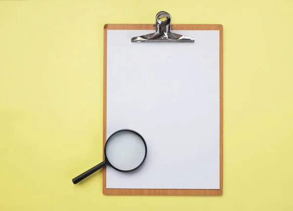Top view of magnifying glass over and Document empty folder on yellow background