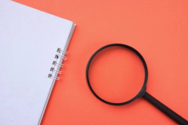 top view a Magnifying glass  with notebook isolate on a orange background. Searching concept.
