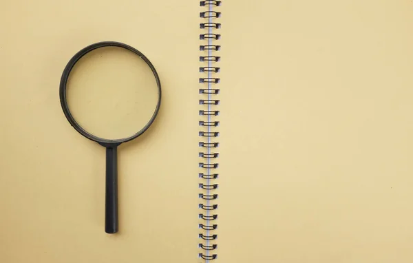 Magnifying glass  with notebook  yellow isolate on a white background. Searching concept.
