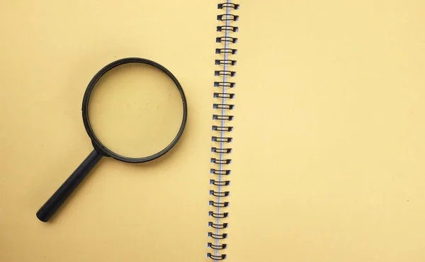 Magnifying glass  with notebook  yellow isolate on a white background. Searching concept.