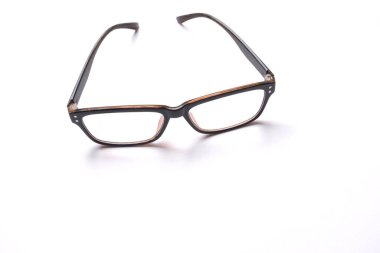 düz bir şekilde siyah çerçeveli bir gözlük uzanıyordu beyaz bir arkaplanda izole edilmiş.